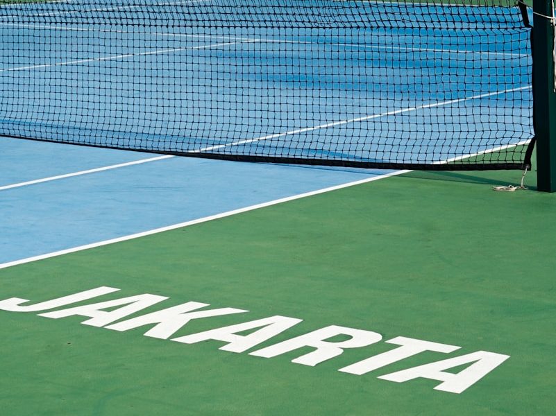 a tennis court with a net and a building in the background